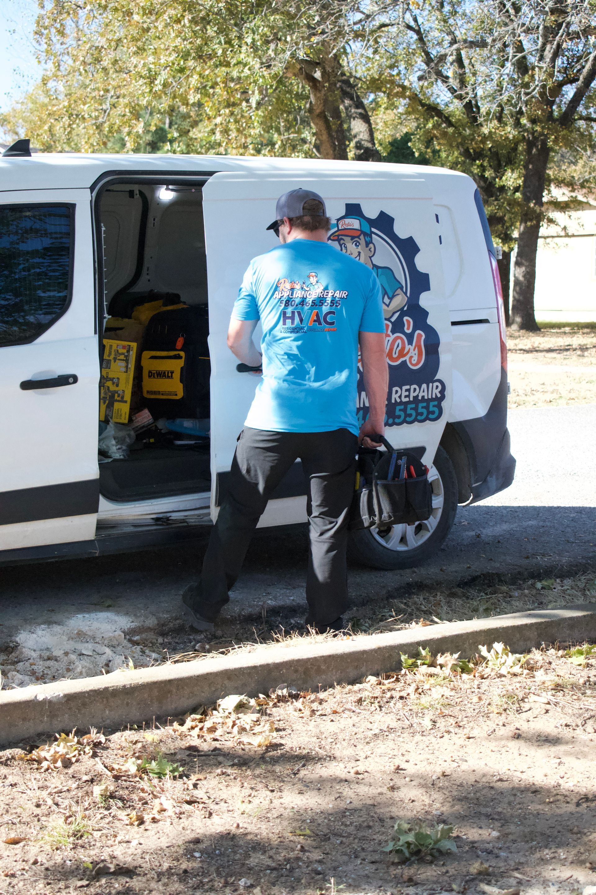 Person loading a yellow tool into a white van with an open side door outdoors