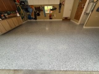 Garage with a light gray speckled epoxy floor.