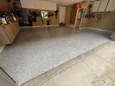 Garage with speckled gray epoxy floor; storage cabinets and tools on walls.
