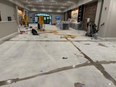 Interior construction site. Concrete floor with utility lines and equipment, partially finished.