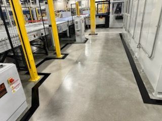 Concrete factory floor with yellow support columns and black painted walkways.