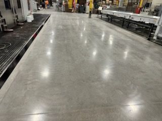 Polished concrete floor reflecting lights in a warehouse.