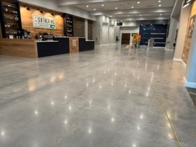 Polished concrete floor in a large lobby with a coffee shop counter in the background.