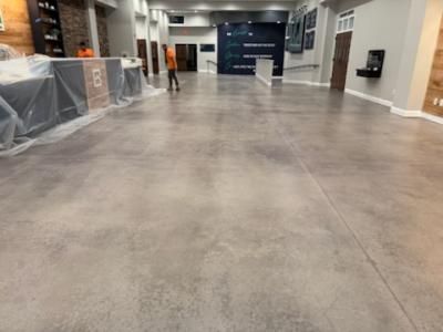Large gray concrete floor in a building interior with a person walking towards the back.