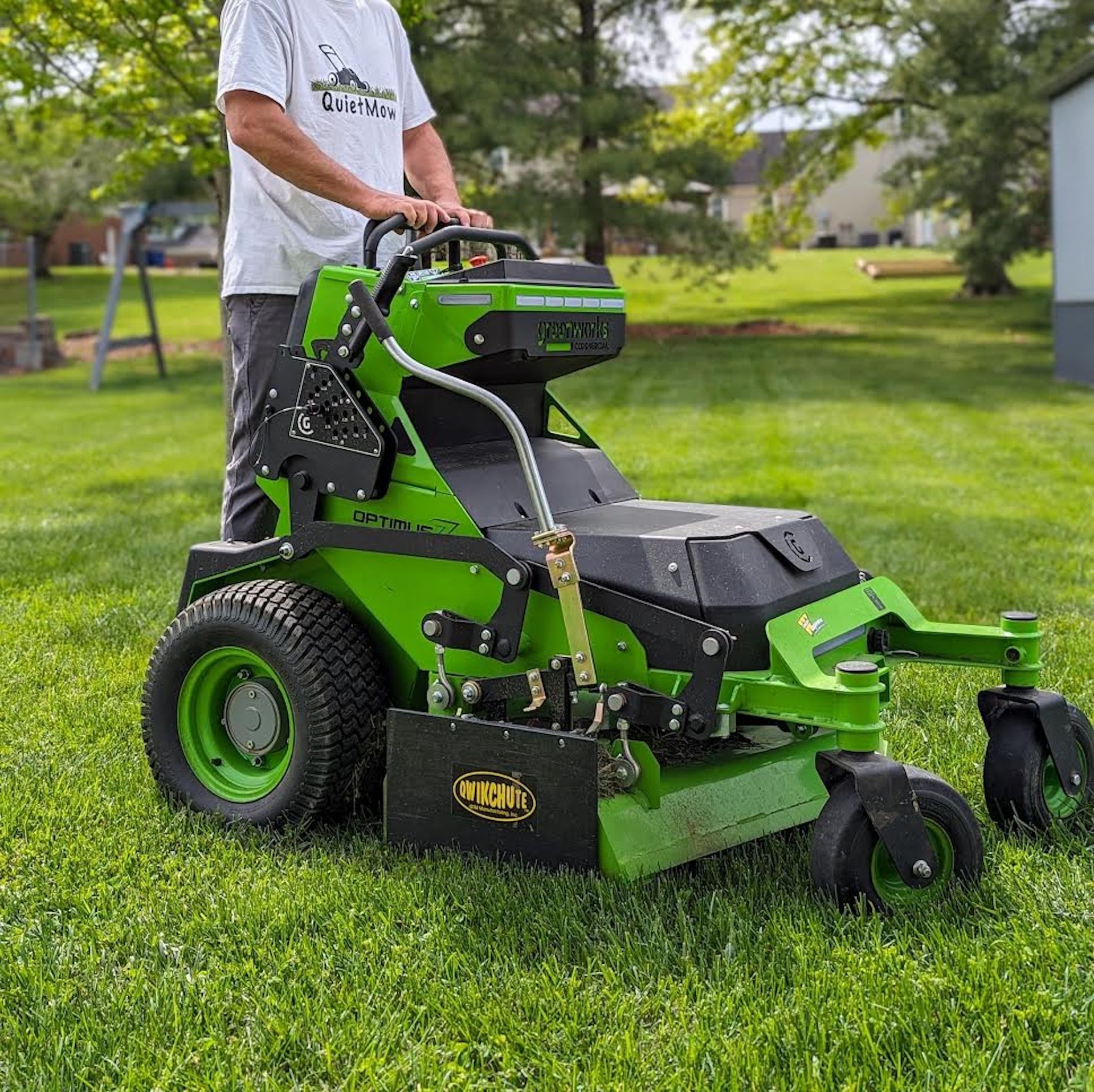 Man mowing lawn with green riding mower.