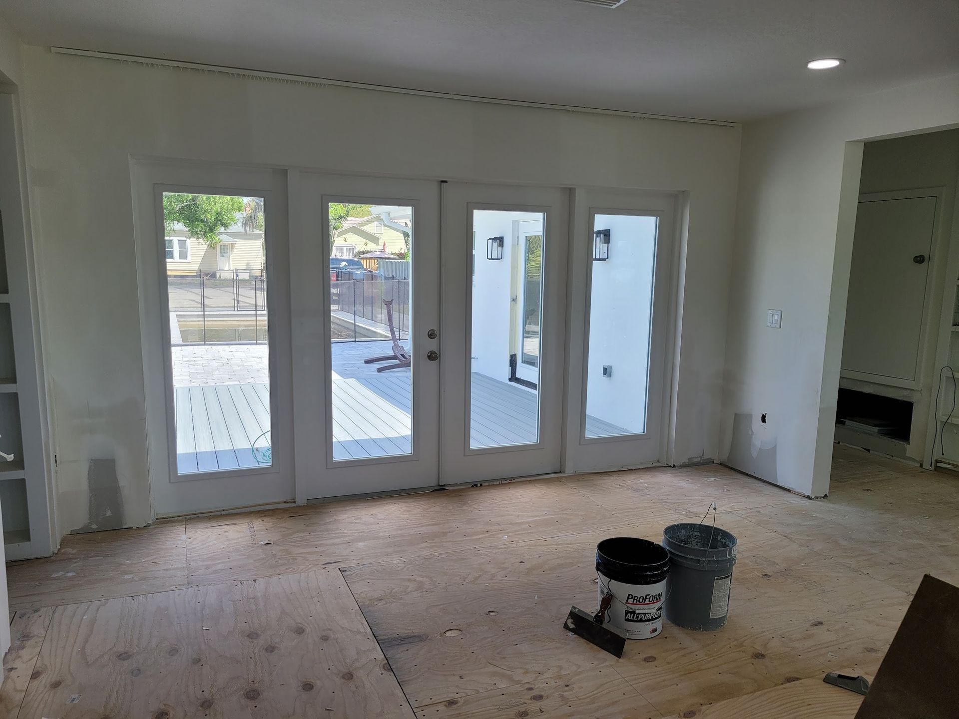 A room with a lot of windows and a bucket of paint on the floor.