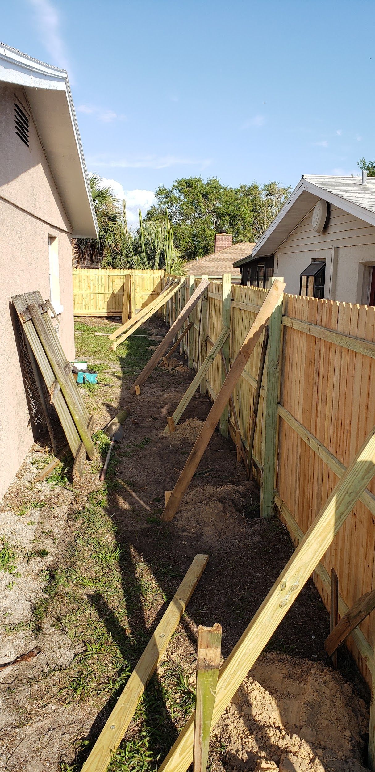 A wooden fence is being built in the backyard of a house.