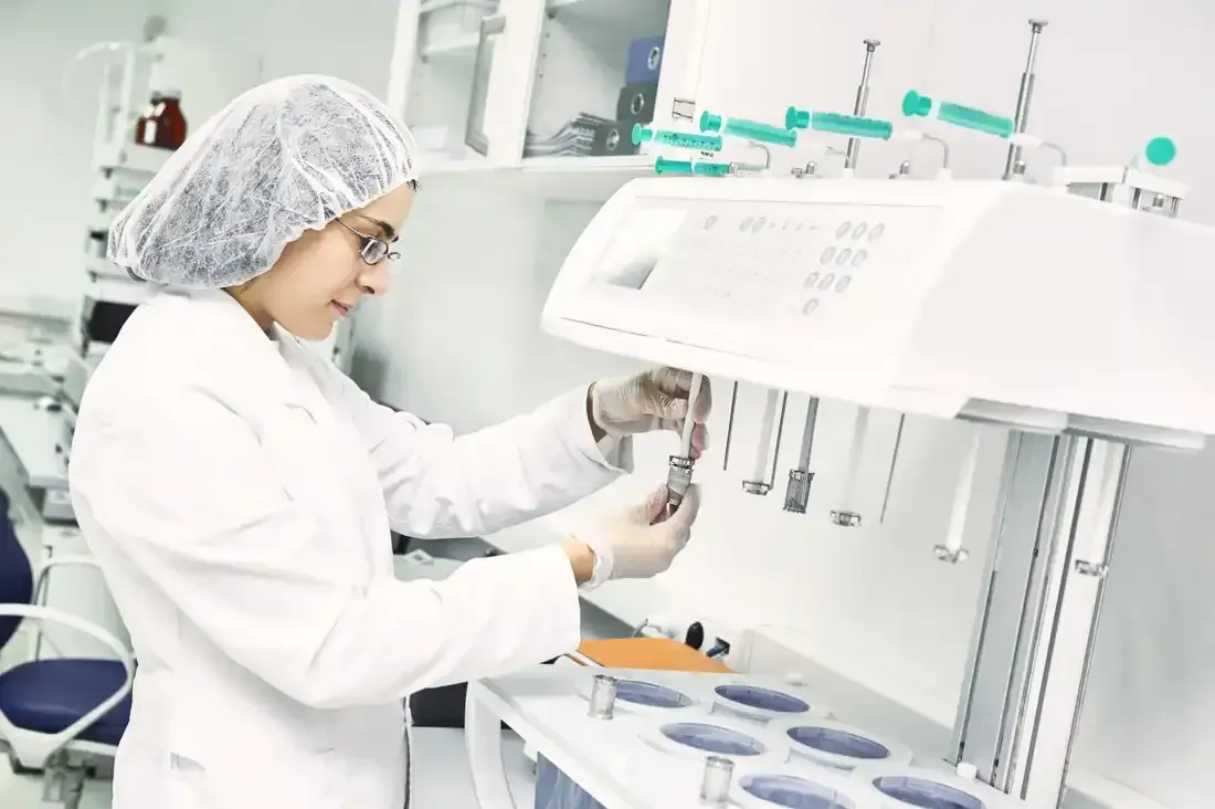 A woman in a lab coat is working on a machine.