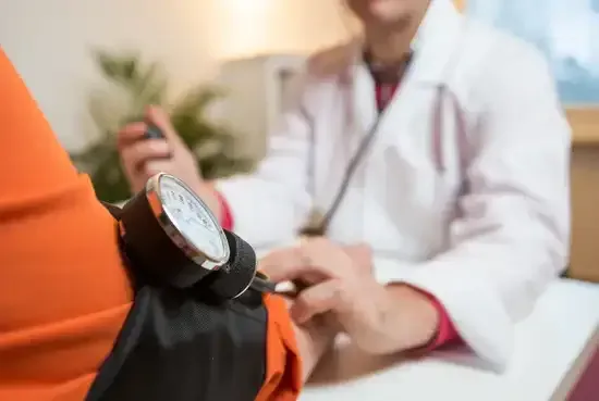 Un médecin prend la tension artérielle d'un patient à l'aide d'un stéthoscope dans son cabinet.