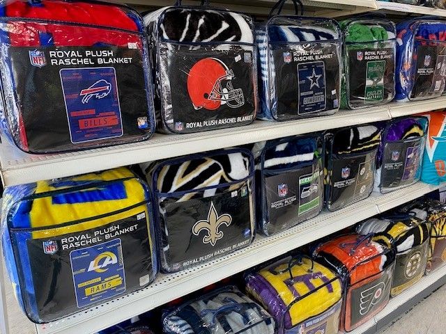 Shelf of sports-themed toiletry bags in assorted colors and team logos.