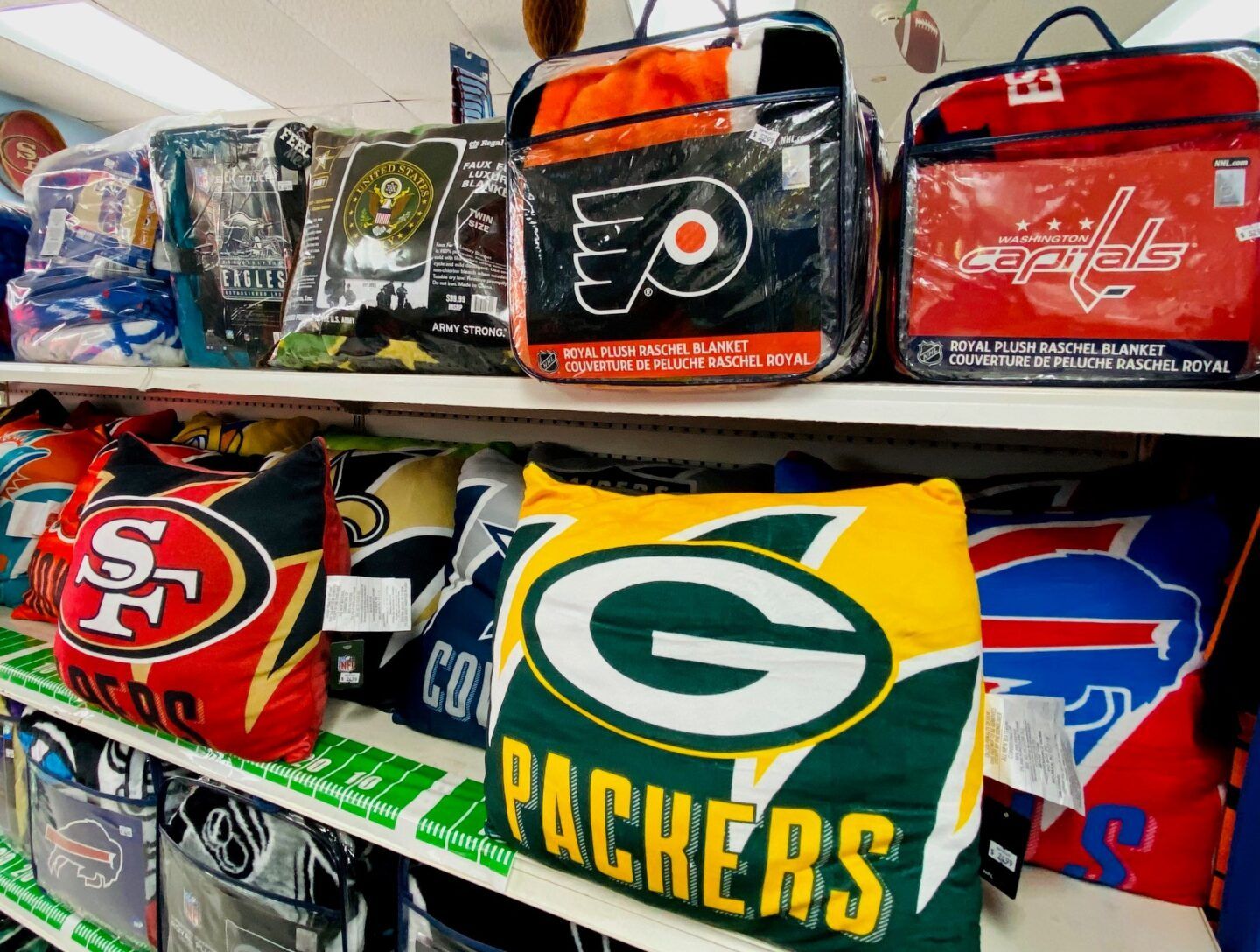 Shelves of NFL team blankets and throws, including Packers, 49ers, Flyers, and Bills designs