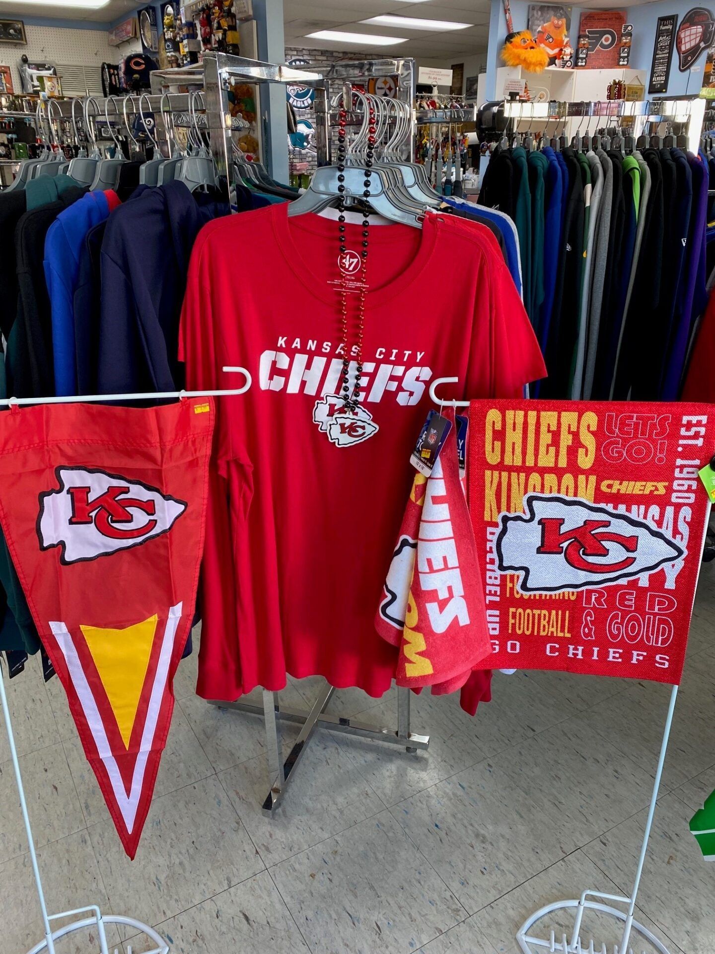 Kansas City Chiefs fan merchandise display with red shirts, towel, and pennant in a store
