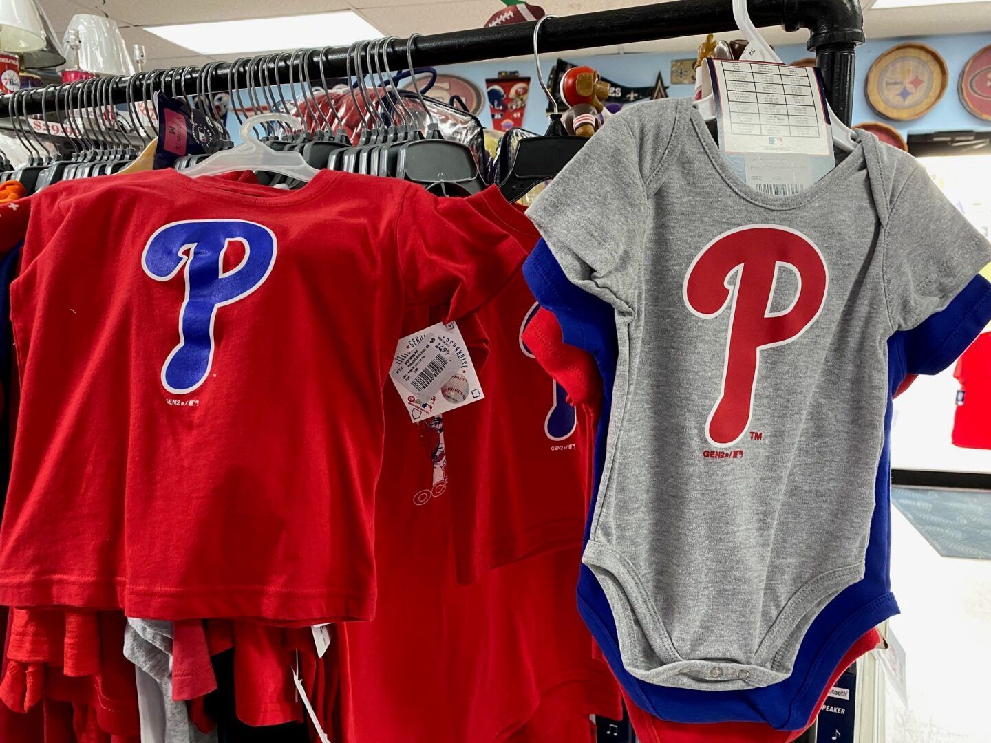 Red and gray baby onesies with blue-and-red “P” logos hanging on display racks.