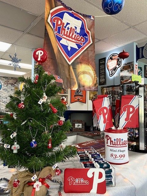 Holiday-decorated Phillies shop display with Christmas tree, ornaments, and Phillies merchandise signs