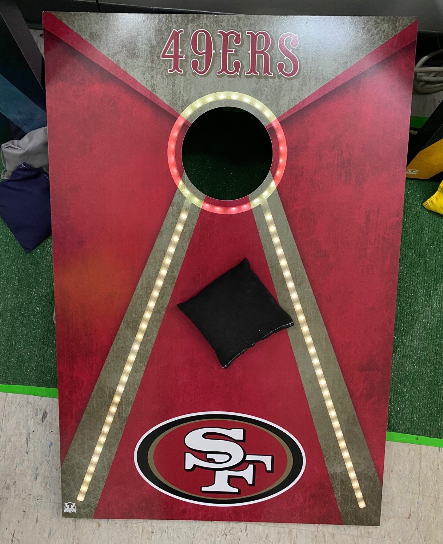 Red San Francisco 49ers cornhole board with logo and lighted side rails.