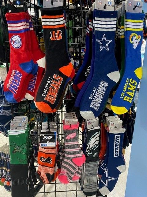 Rack of colorful sports socks with team logos, including red, blue, orange, green, and pink pairs.
