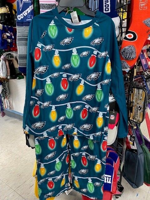 Teal holiday pajamas with football ornaments hanging on a store rack