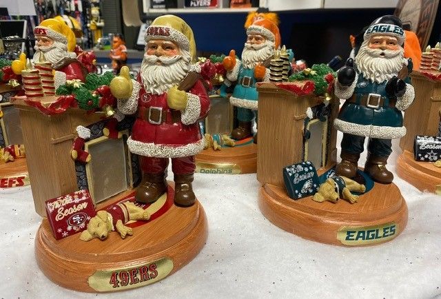 Holiday Santa figurines on wooden bases, including a red-suited Santa and a sailor Santa with gifts and ornaments