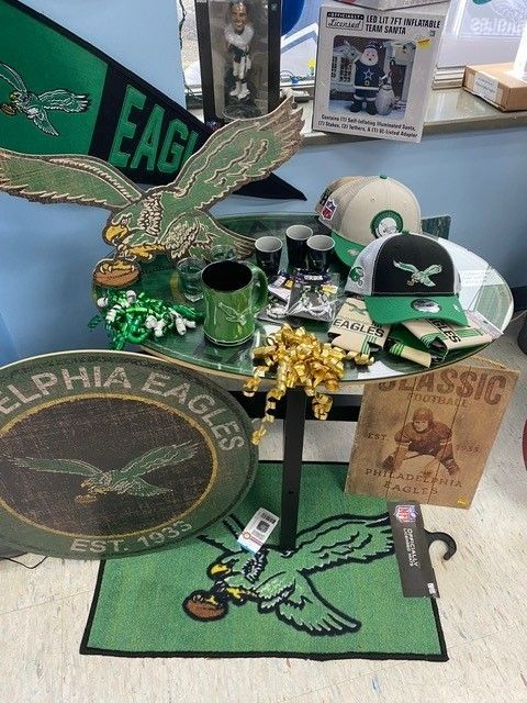 Philadelphia Eagles memorabilia display with green-and-white items, an eagle, cap, mug, and plaques on a table