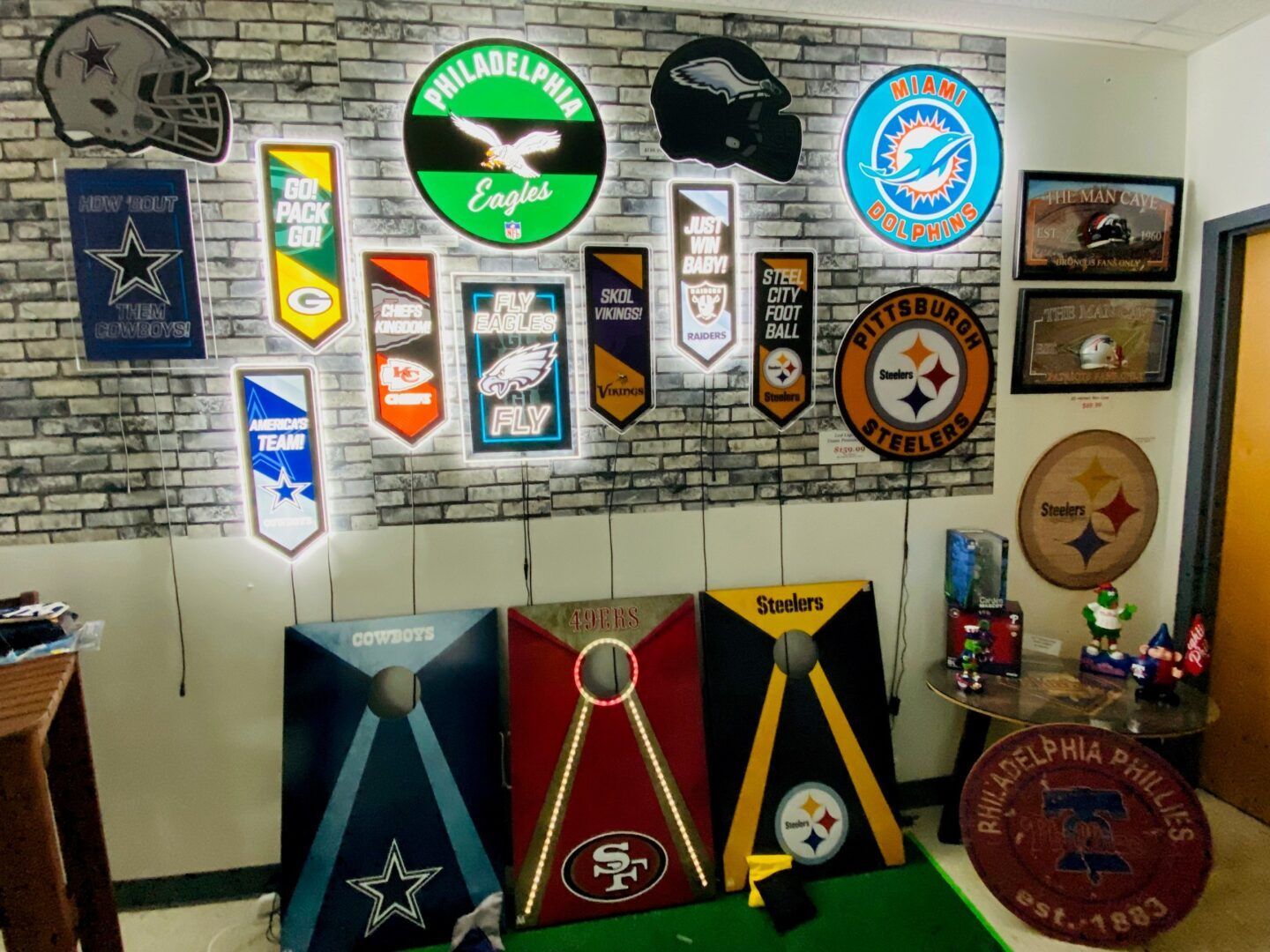 Wall covered with vintage military and team pennants, plaques, and sports memorabilia on a white brick wall
