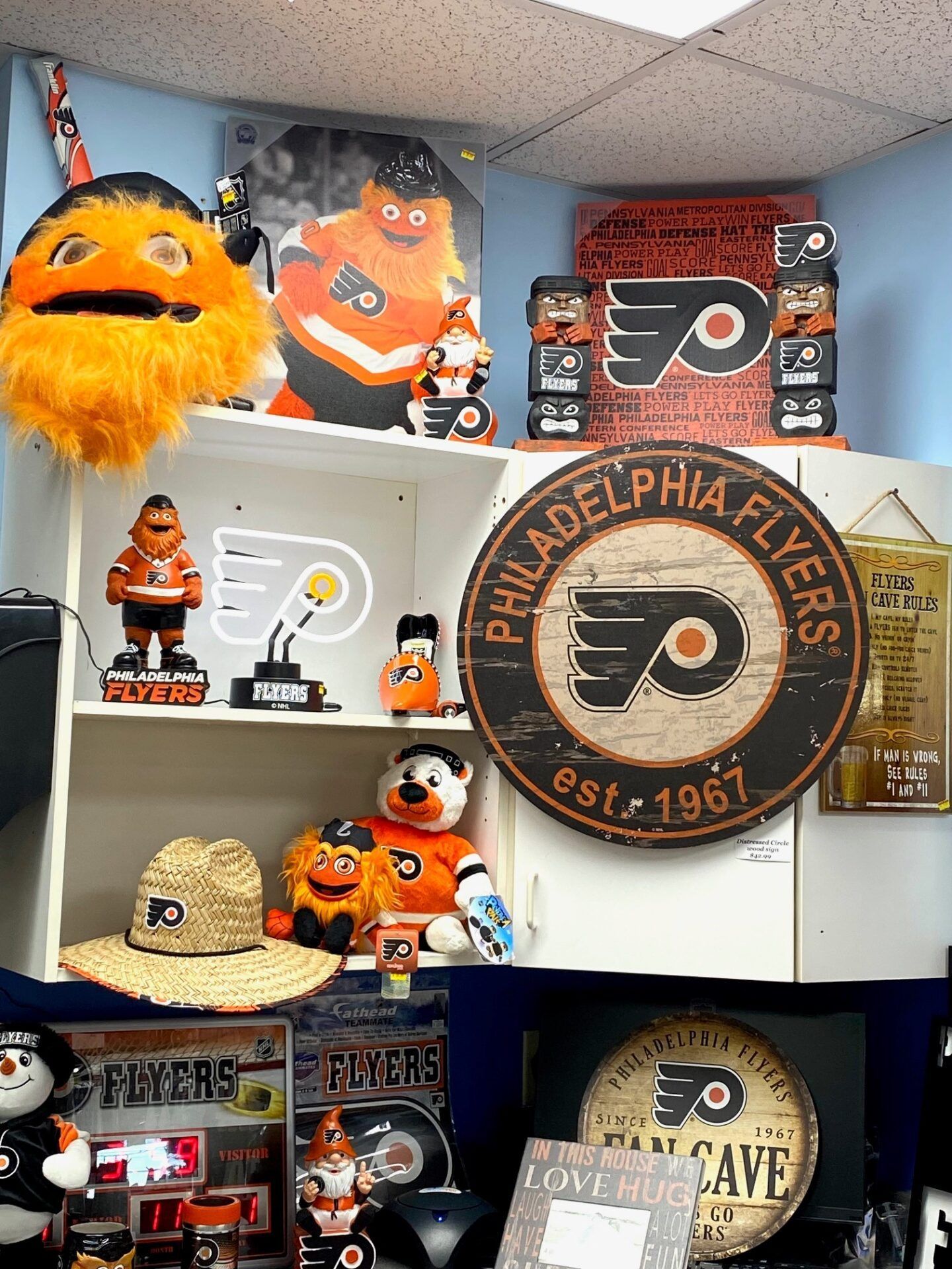 Philadelphia Flyers memorabilia shelf with orange-and-black plush mascots and logos in a display room