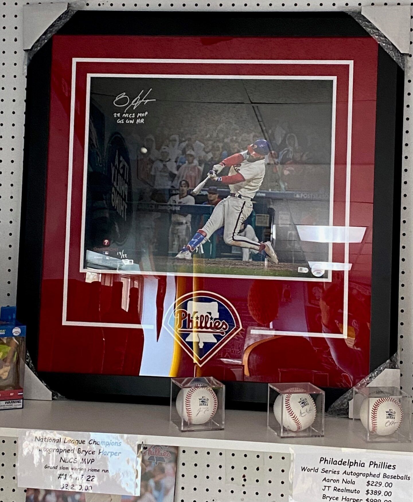 Framed baseball action photo with three baseballs displayed below on a shelf.