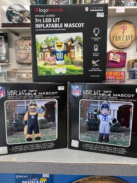 Store shelf with 7-foot LED inflatable mascots in sports team uniforms, boxed in black packaging