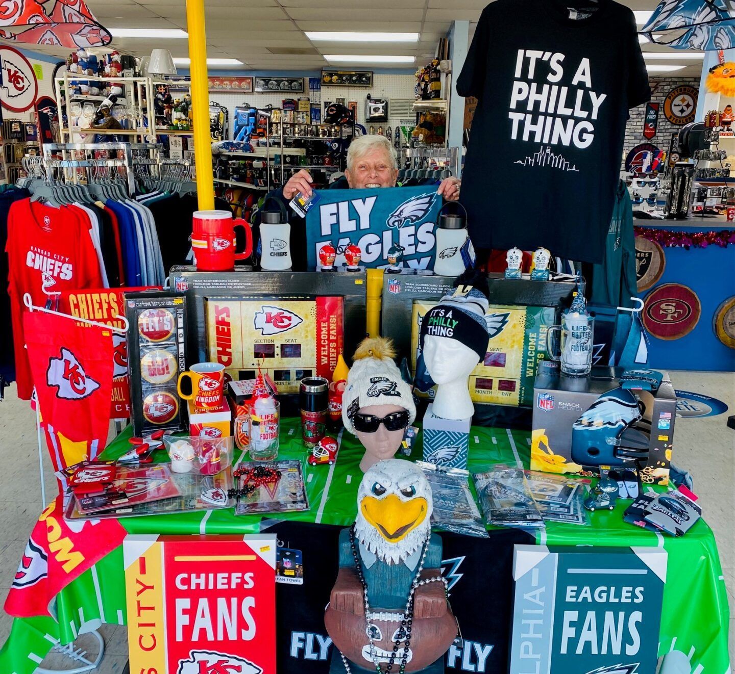 Philly sports merchandise display with Eagles and Chiefs items, shirts, mugs, and signs in a shop