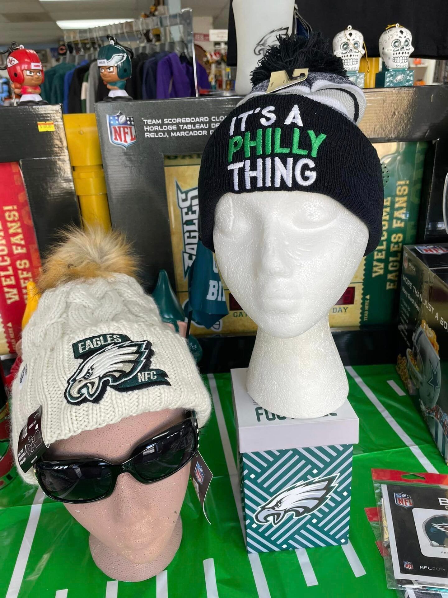 Philadelphia Eagles hats and winter accessories displayed on mannequins at a sports shop.