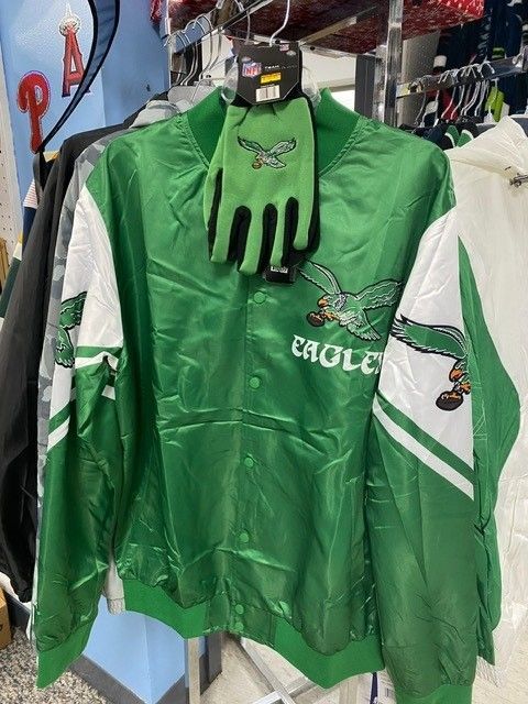 Green Philadelphia Eagles jacket with matching gloves hanging on a store rack.