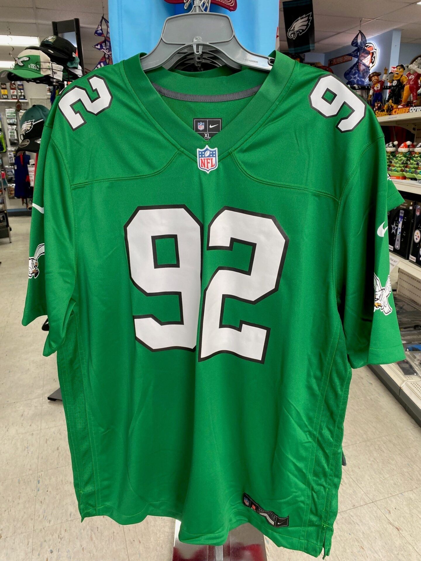 Green NFL jersey with white number 92 hanging on a hanger in a store.