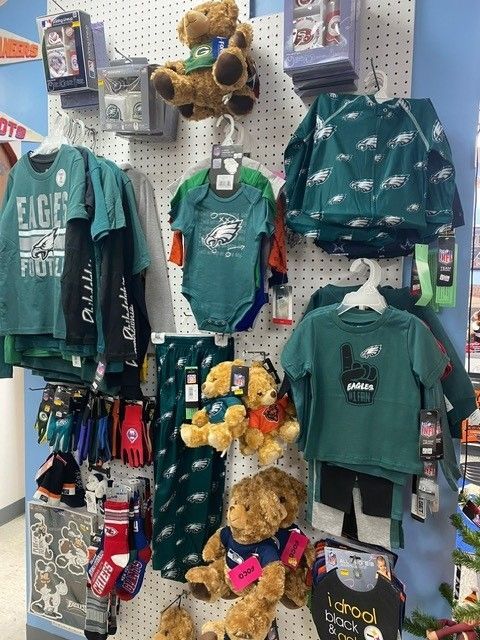 Teal Green Bay Packers holiday-themed clothing and teddy bears displayed on a store rack