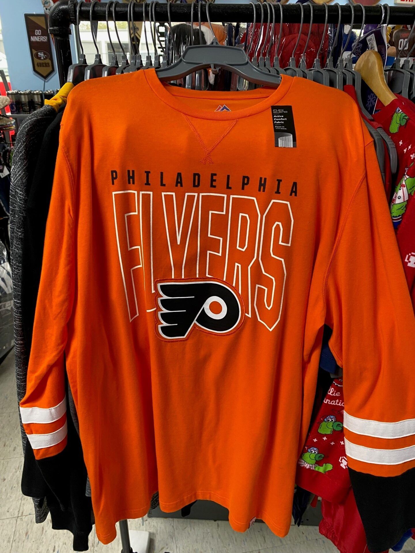 Orange Philadelphia Flyers hockey jersey hanging on a rack, with black and white sleeve stripes.