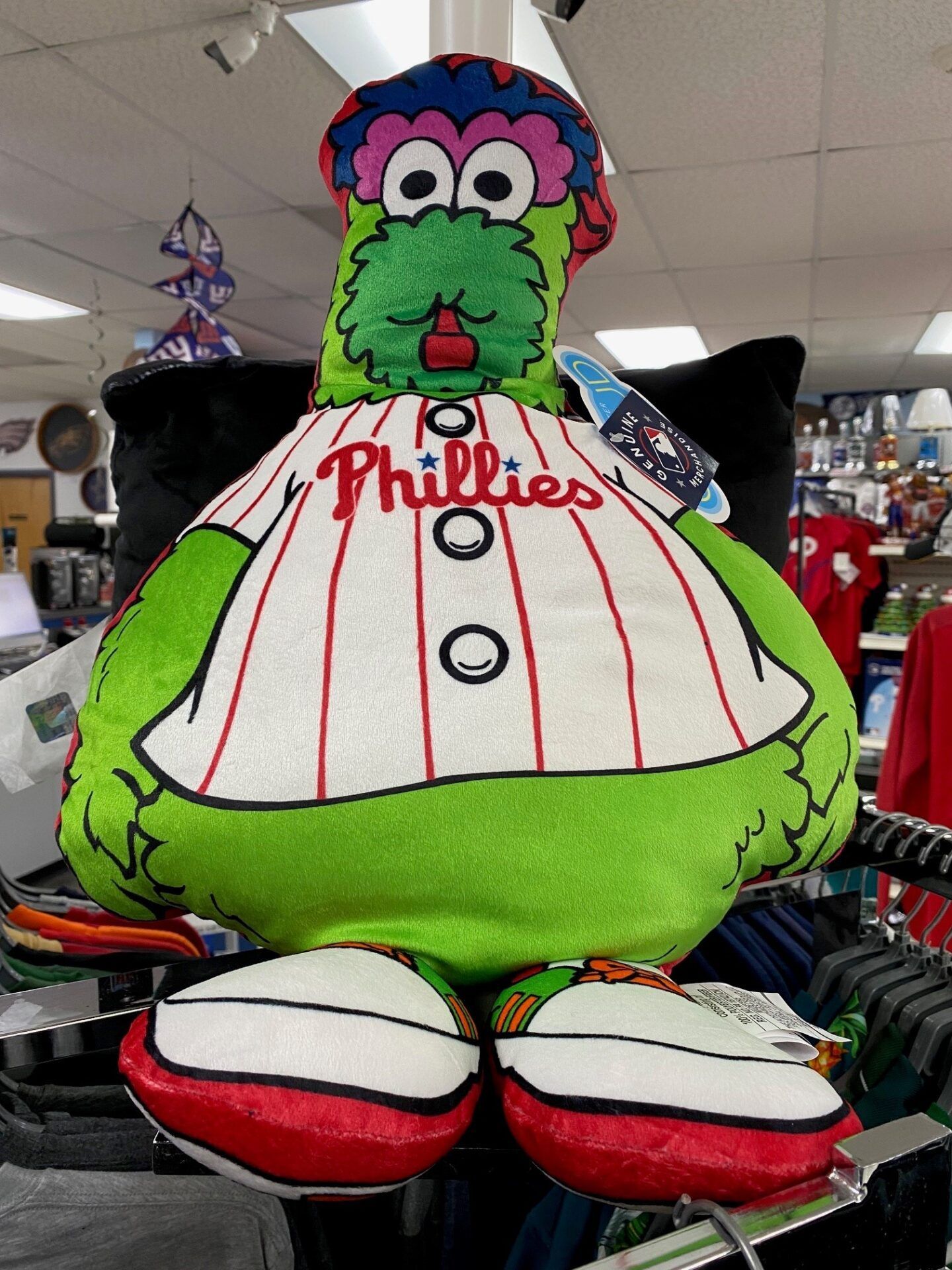 Green Phillies mascot balloon in a white pinstriped jersey and red shoes, hanging indoors