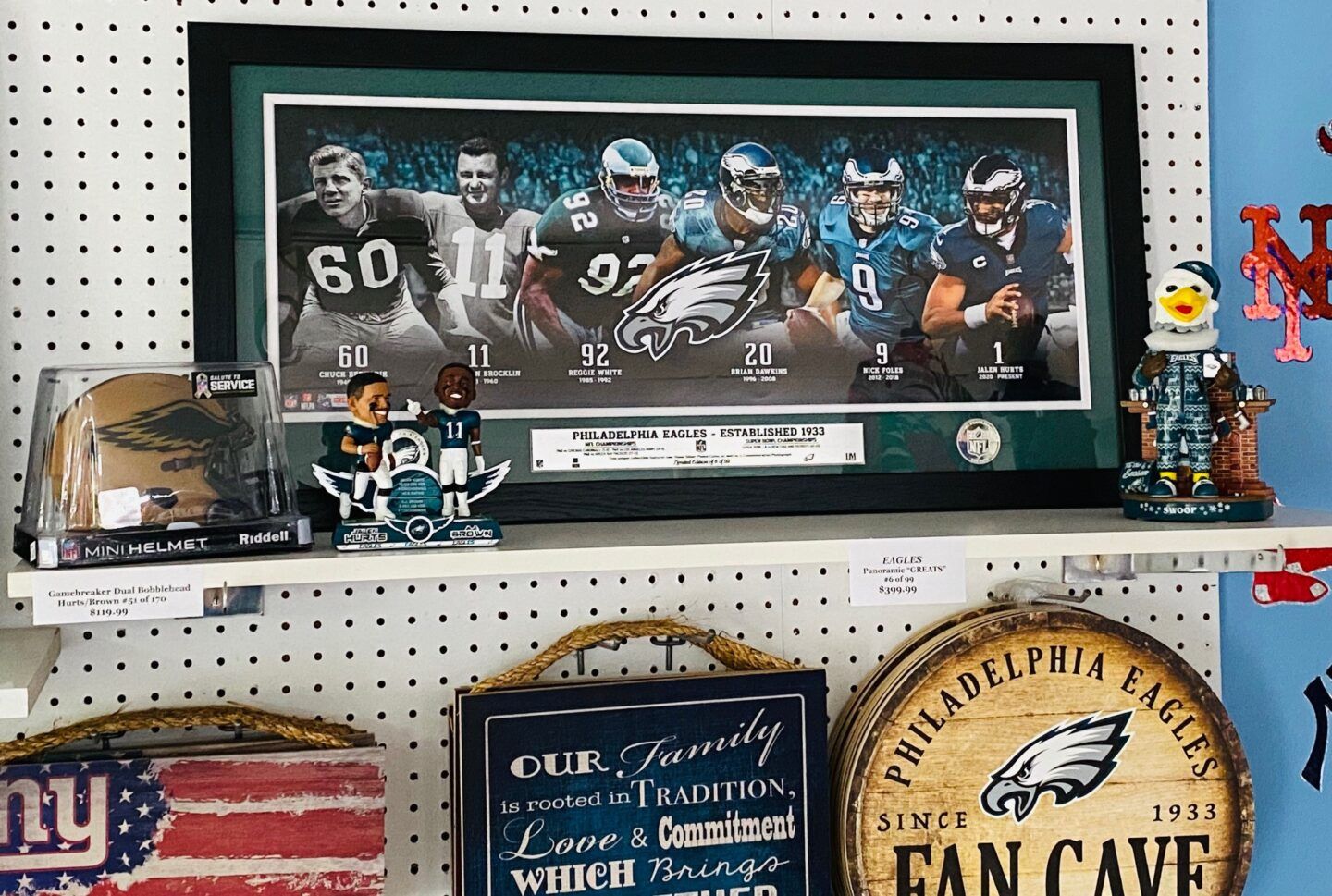 Sports fan display with framed football photo, memorabilia, and team signs on shelves against a pegboard wall