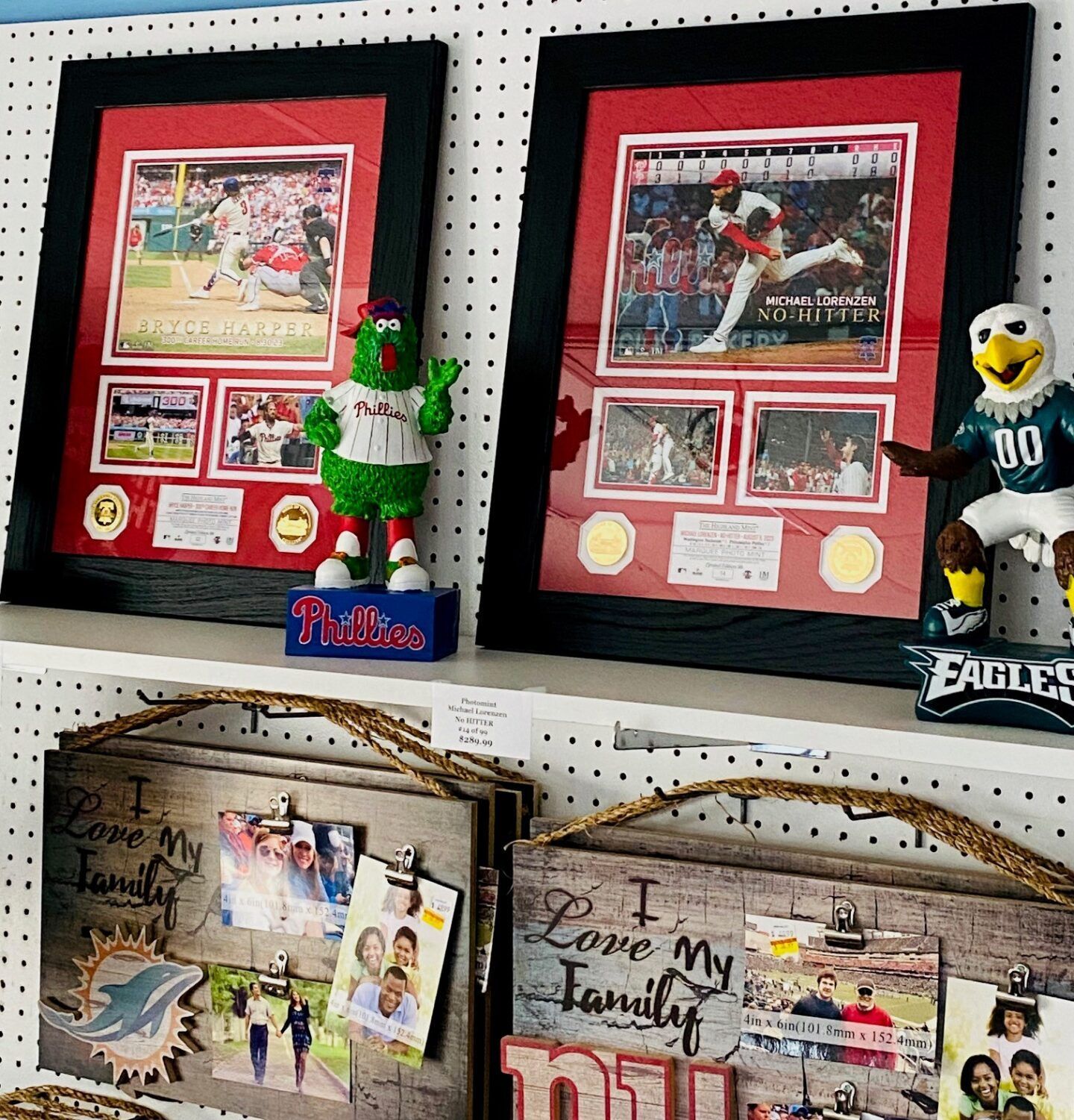 Framed sports scrapbooks and memorabilia displayed on a pegboard wall with plush team mascots.