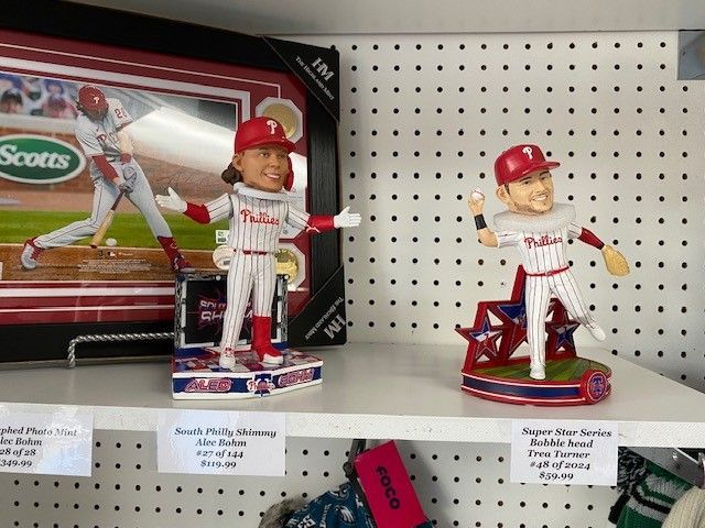 Two baseball bobbleheads on a store shelf, one in a red-striped uniform and one on a star base.