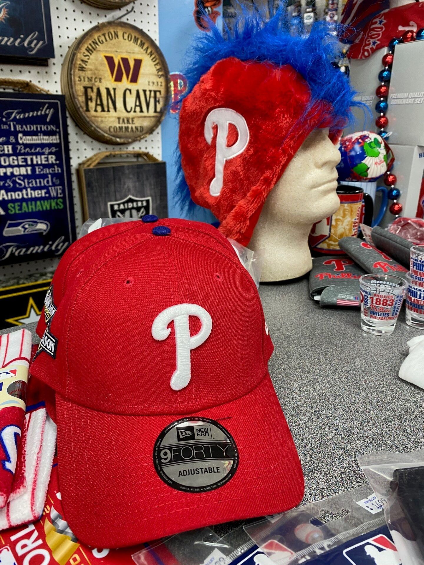Red Philadelphia Phillies cap in front of a mannequin head wearing a red-and-blue “P” hat and scarf.