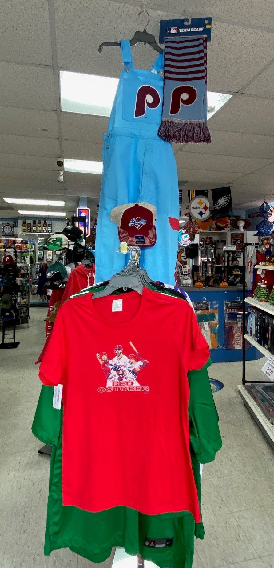 Blue llama costume hanging above red and green T-shirts in a store aisle