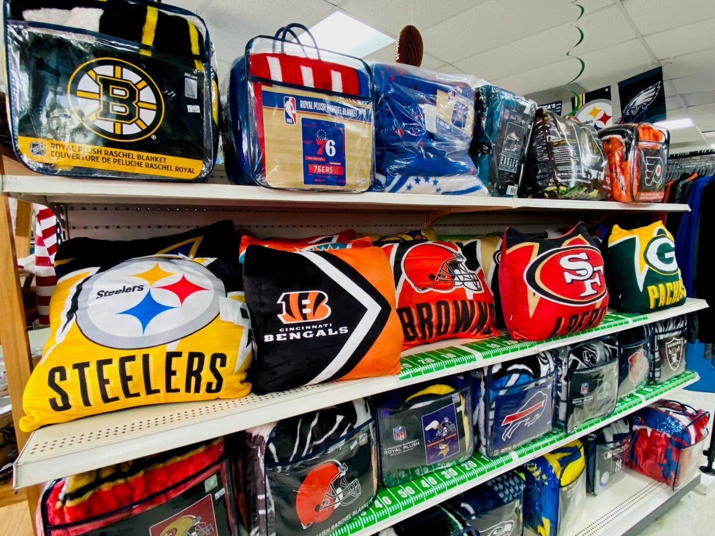 Shelves of colorful NFL team blankets and pillows on display in a store