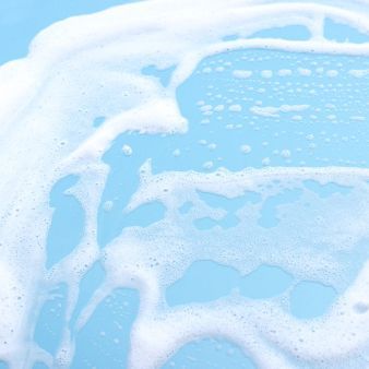 White foam and bubbles swirling over light blue water or surf.