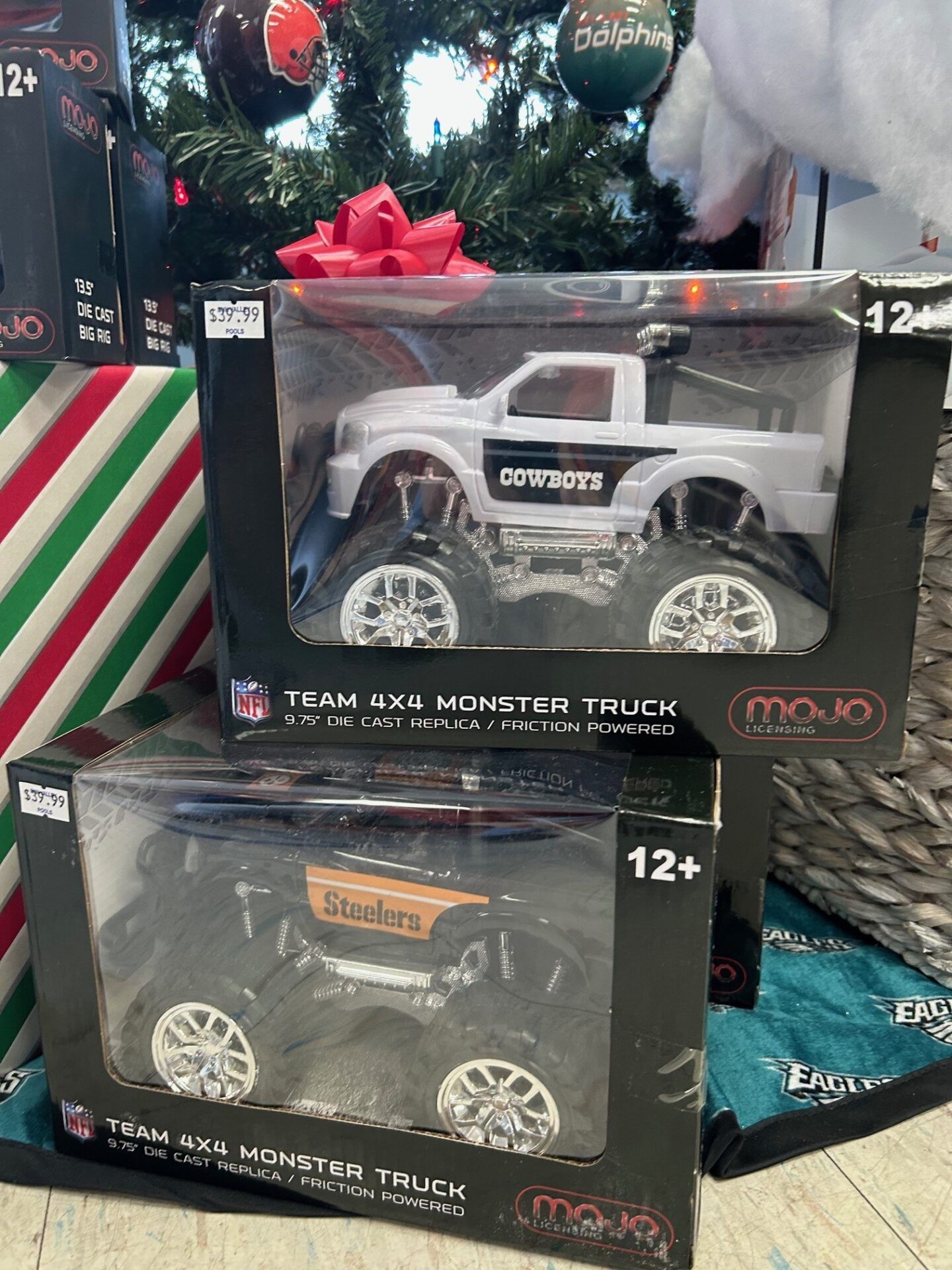 Toy monster trucks in boxed packaging on a holiday display, one white and one black.