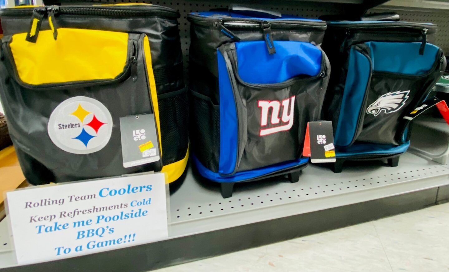 Three team-branded cooler bags on a shelf beside a sign about mobile coolers for tailgate events