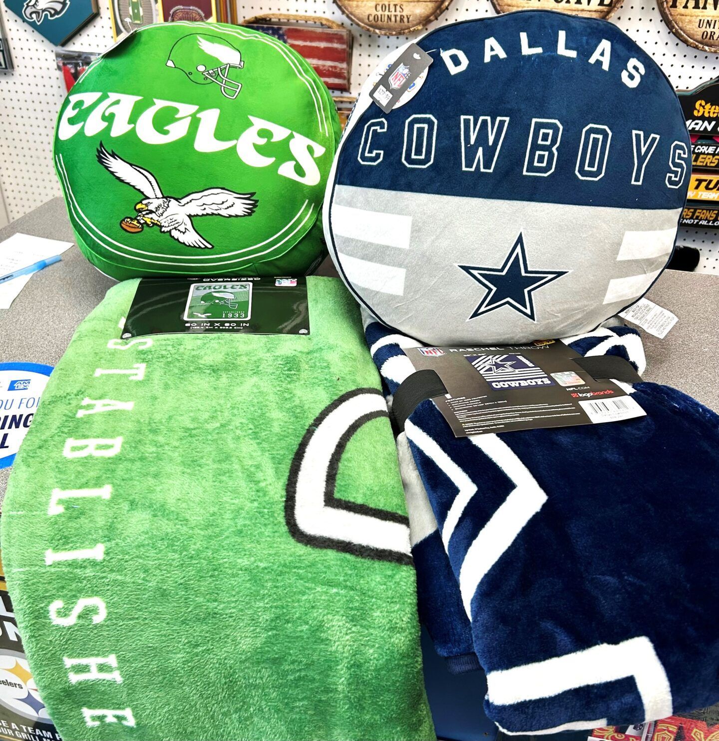 Philadelphia Eagles and Dallas Cowboys sports-themed pillows and blankets in green, blue, and gray.