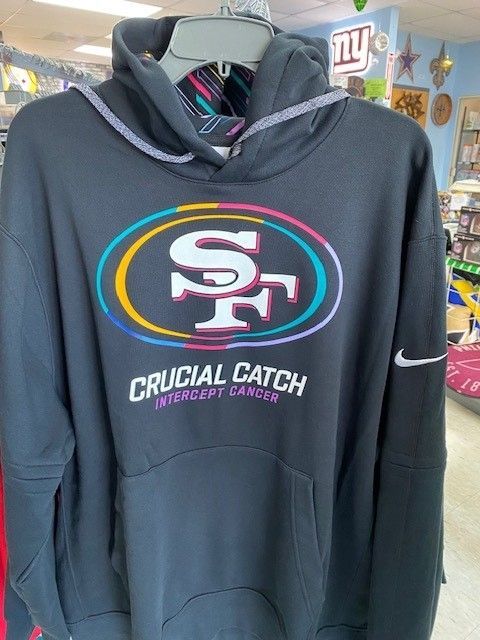 Black San Francisco 49ers hoodie with colorful logo and “Crucial Catch” text hanging on a hanger