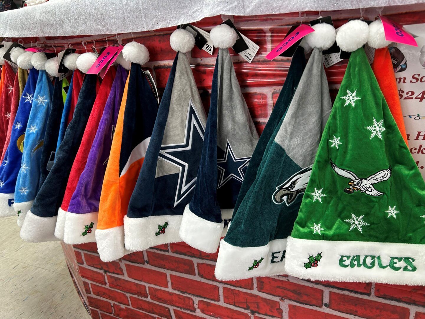 Christmas tree skirts and stockings with NFL team logos hanging on a brick wall display