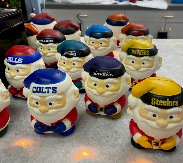 Mini sports-themed figurines with NFL team logos, including Bills, Bears, Ravens, Colts, Panthers, and Steelers, on a countertop