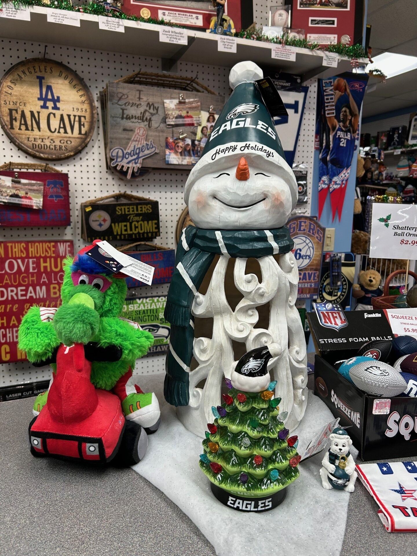 Holiday display with a snowman and green dinosaur figurines among sports-themed decorations and souvenirs