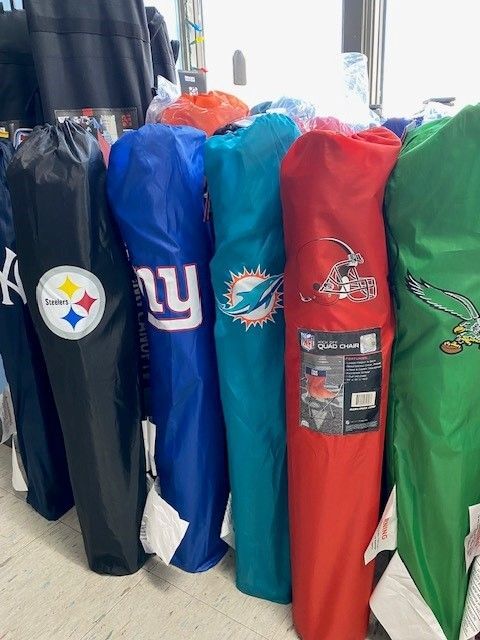 Several hanging NFL team jackets in black, blue, teal, red, and green, displayed indoors.