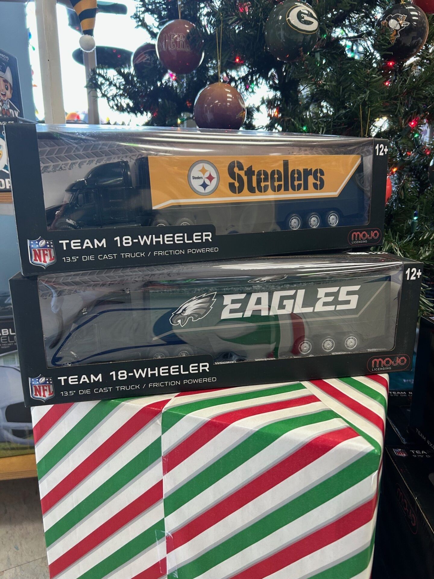 Steeler and Eagles NFL gift boxes stacked under a decorated Christmas tree